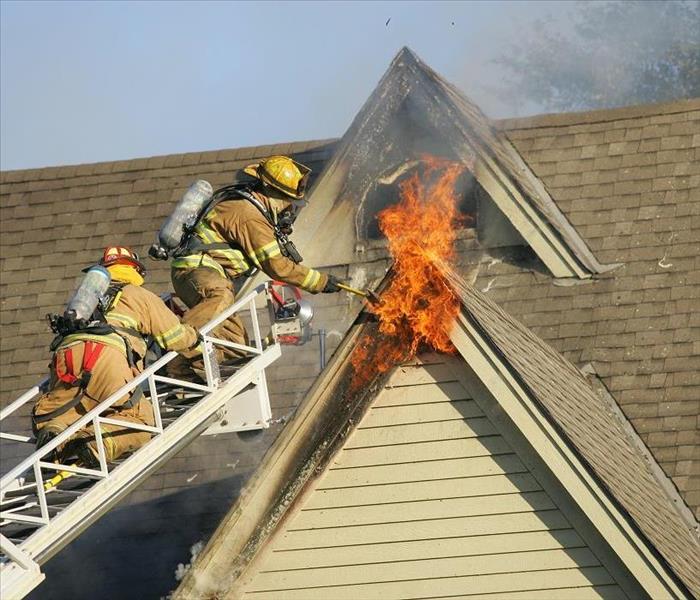 Firemen on ladder extinguishing a 2nd story fire